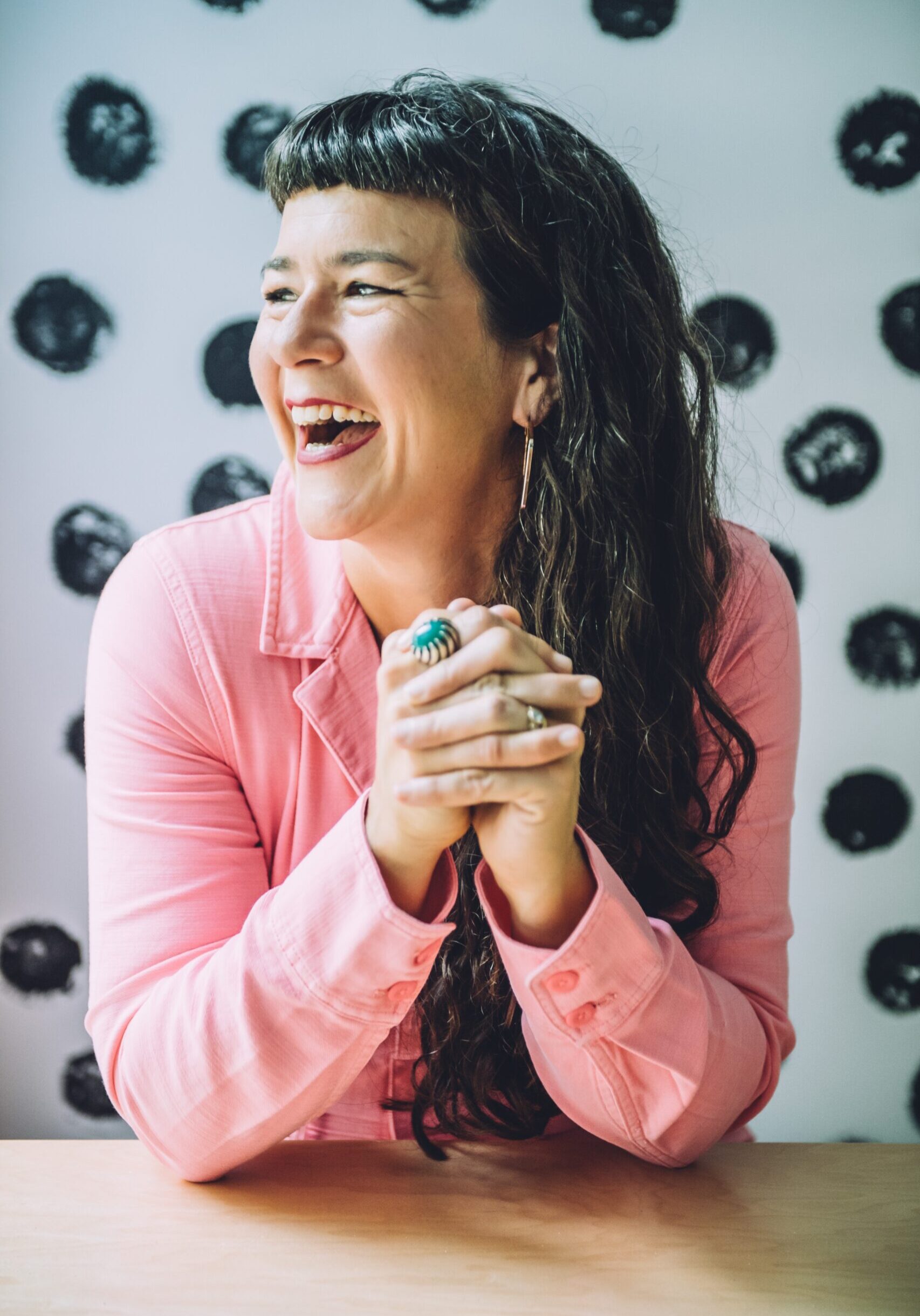 Life coach Beatriz Victoria Albina in a pink jumpsuit, smiling while sitting at a table